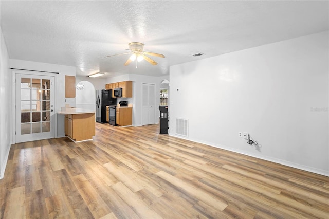 1106 Alpine Ave NW, Palm Bay, FL 32907 - unfurnished living room featuring light wood-type flooring, ceiling fan, arched walkways, baseboards, and a textured ceiling