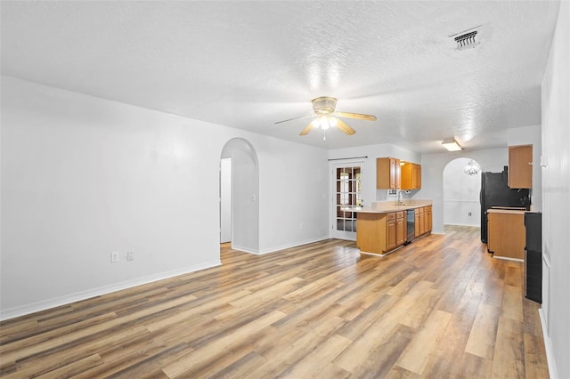 1106 Alpine Ave NW, Palm Bay, FL 32907 - unfurnished living room with arched walkways, ceiling fan, light wood-type flooring, baseboards, and a textured ceiling