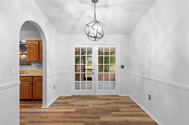1106 Alpine Ave NW, Palm Bay, FL 32907 - unfurnished dining area with wood finished floors, a chandelier, french doors, and arched walkways