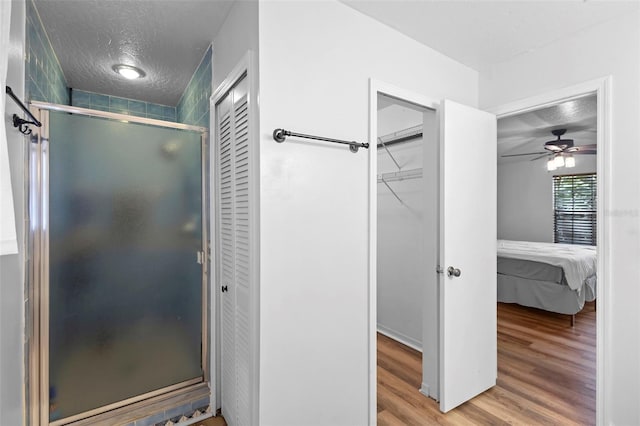 1106 Alpine Ave NW, Palm Bay, FL 32907 - full bathroom featuring wood finished floors, a textured ceiling, a shower stall, a ceiling fan, and ensuite bathroom