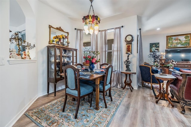 8721 Crystal Creek Ct, Land O Lakes, FL 34638 - dining room with a chandelier, arched walkways, wood finished floors, and baseboards