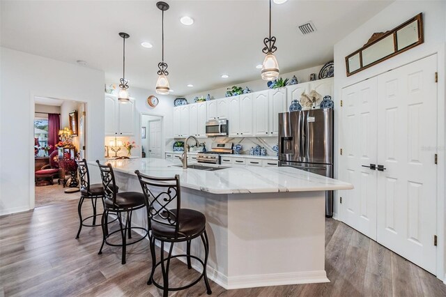 8721 Crystal Creek Ct, Land O Lakes, FL 34638 - kitchen with stainless steel appliances, a sink, light wood finished floors, recessed lighting, and white cabinetry