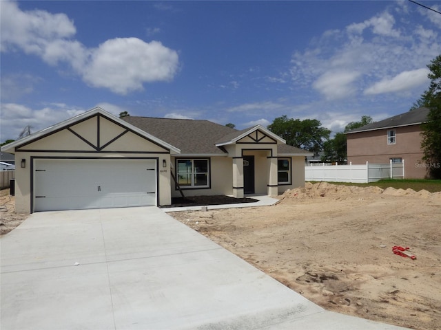 view of front of home featuring an attached garage, fence, concrete driveway, and stucco siding