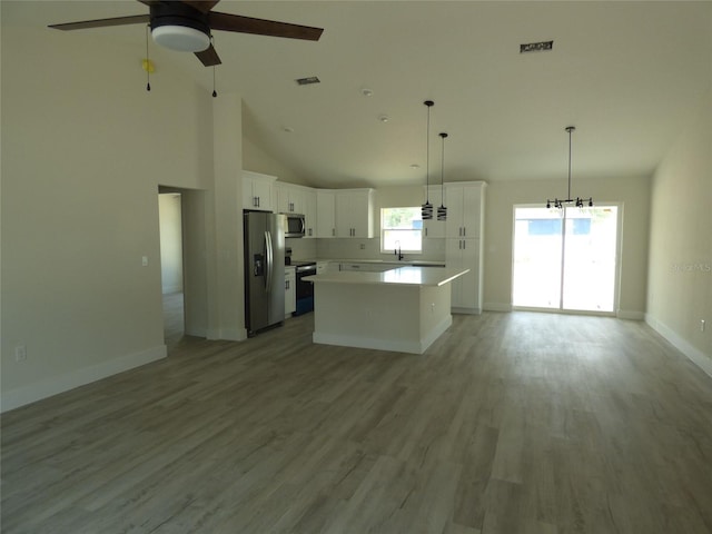 kitchen featuring appliances with stainless steel finishes, open floor plan, a ceiling fan, white cabinets, and a kitchen island
