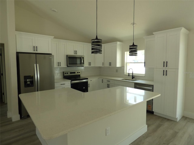 kitchen featuring appliances with stainless steel finishes, a sink, light wood-style flooring, decorative backsplash, and lofted ceiling