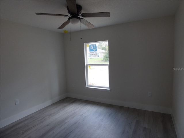 unfurnished room featuring baseboards, wood finished floors, and ceiling fan