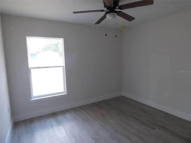unfurnished room featuring wood finished floors, baseboards, and a ceiling fan