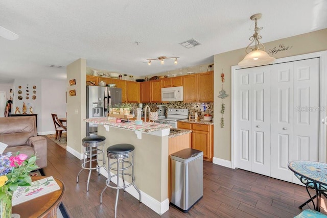 13480 Applerose Ln Unit 19, Orlando, FL 32824 - kitchen featuring white appliances, dark wood-style flooring, hanging light fixtures, a textured ceiling, and a kitchen island with sink