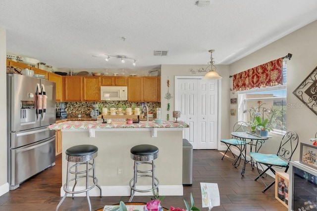 13480 Applerose Ln Unit 19, Orlando, FL 32824 - kitchen featuring stainless steel fridge, white microwave, backsplash, light countertops, and a breakfast bar area
