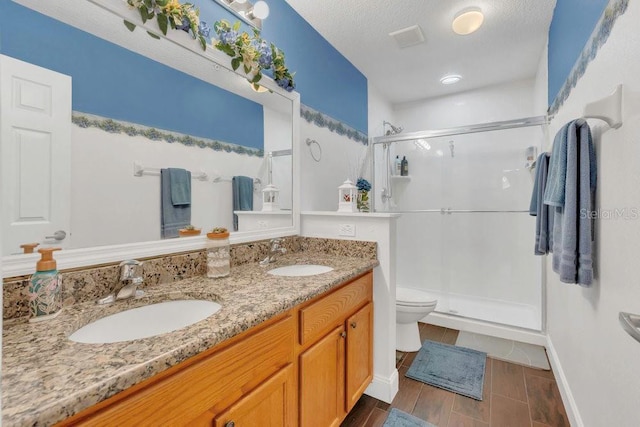 13480 Applerose Ln Unit 19, Orlando, FL 32824 - bathroom with a stall shower, toilet, double vanity, baseboards, and a textured ceiling