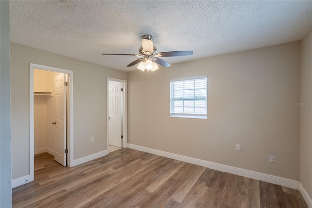 4827 Elese St, Orlando, FL 32811 - unfurnished bedroom featuring wood finished floors, a walk in closet, baseboards, a closet, and a textured ceiling