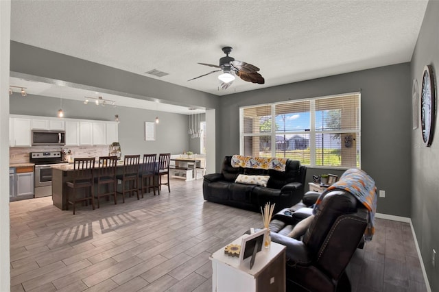 1744 Pine Ridge Dr, Davenport, FL 33896 - living room featuring a textured ceiling, ceiling fan, and light wood-style floors