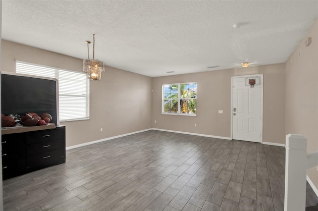 1744 Pine Ridge Dr, Davenport, FL 33896 - unfurnished living room with a textured ceiling, wood finished floors, baseboards, a ceiling fan, and a chandelier