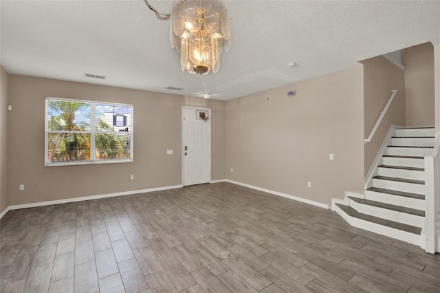 1744 Pine Ridge Dr, Davenport, FL 33896 - unfurnished living room with wood finished floors, a chandelier, stairway, baseboards, and a textured ceiling