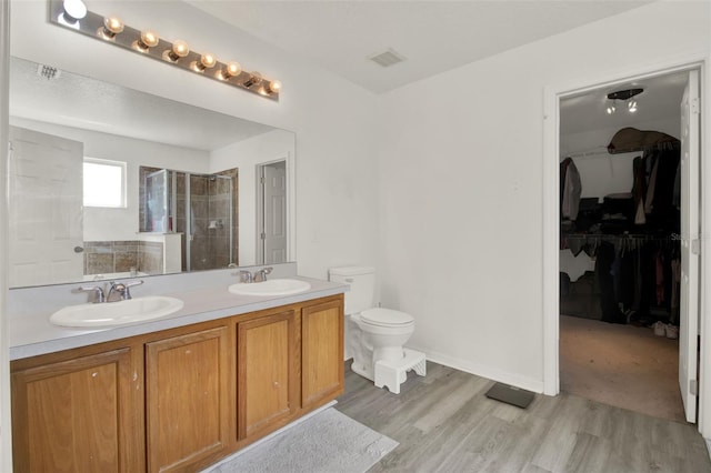 1744 Pine Ridge Dr, Davenport, FL 33896 - bathroom with a stall shower, double vanity, a spacious closet, wood finished floors, and toilet