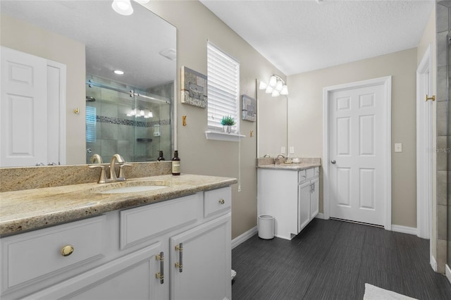 308 Michael Blake Blvd, Winter Springs, FL 32708 - full bathroom featuring baseboards, a shower stall, two vanities, wood finished floors, and a textured ceiling