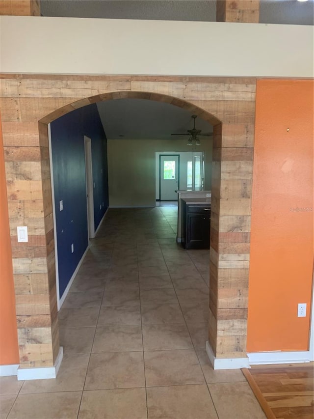 701 Twin Lake Ave, Deltona, FL 32738 - hallway featuring wood walls, arched walkways, baseboards, and light tile patterned flooring