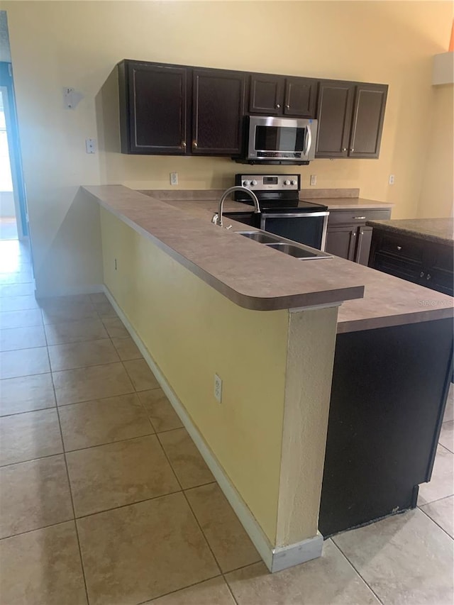 701 Twin Lake Ave, Deltona, FL 32738 - kitchen featuring stainless steel appliances, light tile patterned flooring, light countertops, a peninsula, and a sink