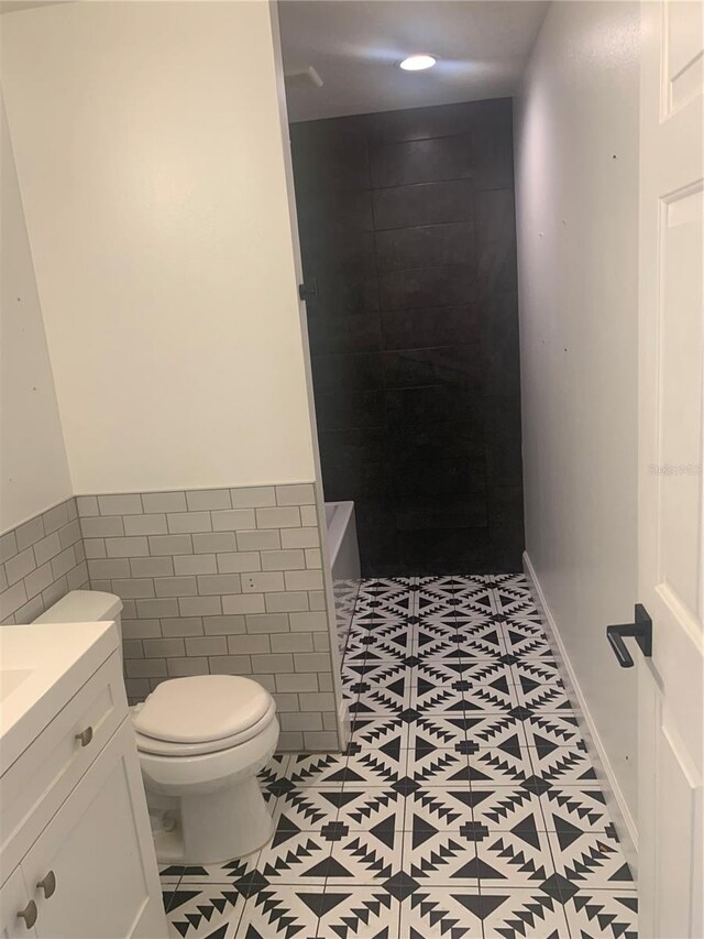 701 Twin Lake Ave, Deltona, FL 32738 - bathroom with toilet, tile patterned flooring, tile walls, a shower, and vanity