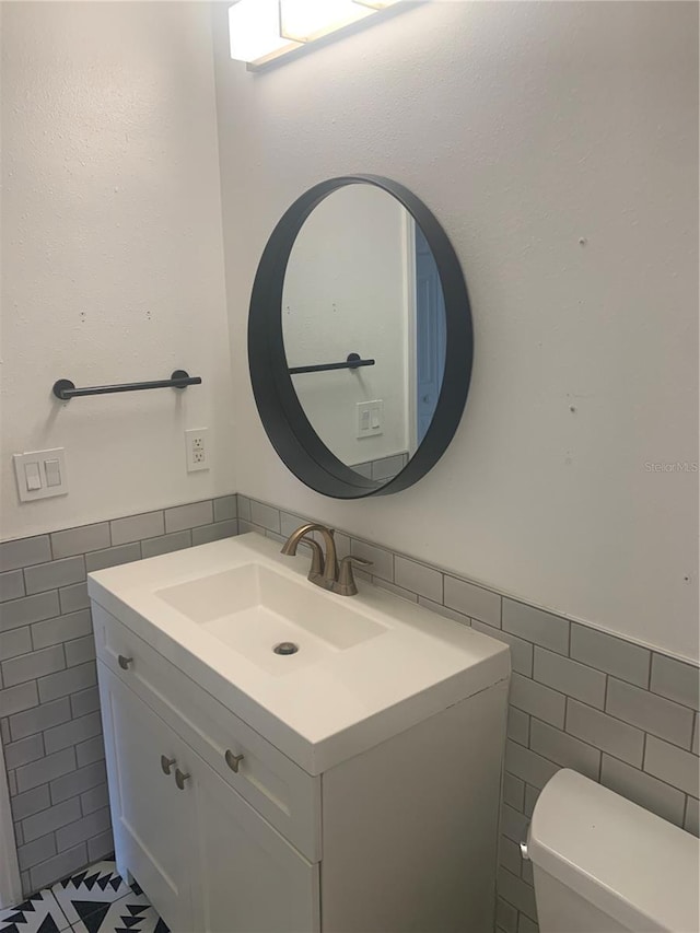 701 Twin Lake Ave, Deltona, FL 32738 - half bathroom featuring tile walls, toilet, vanity, wainscoting, and tile patterned floors