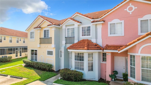 multi unit property featuring a tile roof, stucco siding, and a front yard