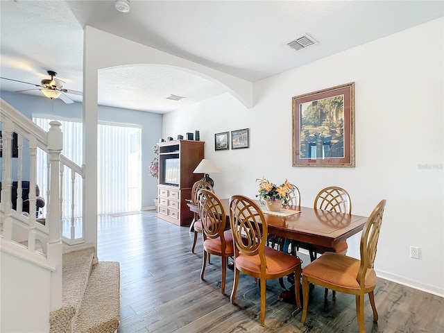 dining area with arched walkways, ceiling fan, wood finished floors, and baseboards