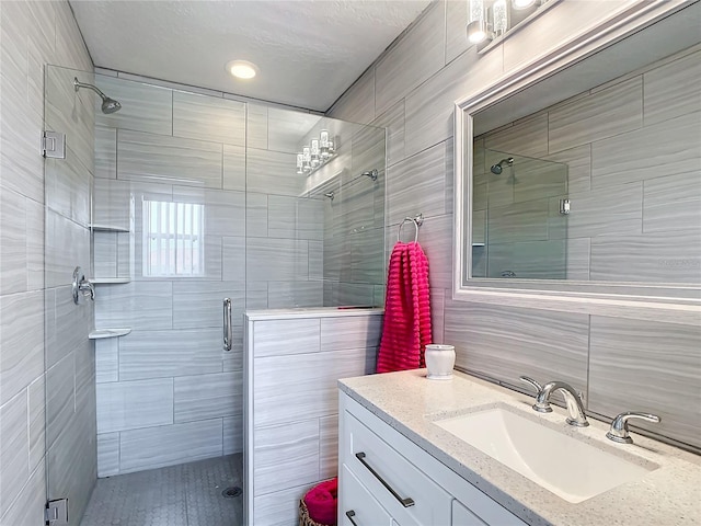 bathroom with tile walls, a shower stall, vanity, and decorative backsplash