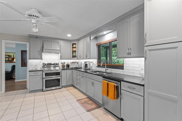 711 Valencia Ct, Winter Garden, FL 34787 - kitchen with stainless steel appliances, a sink, gray cabinets, ceiling fan, and dark countertops