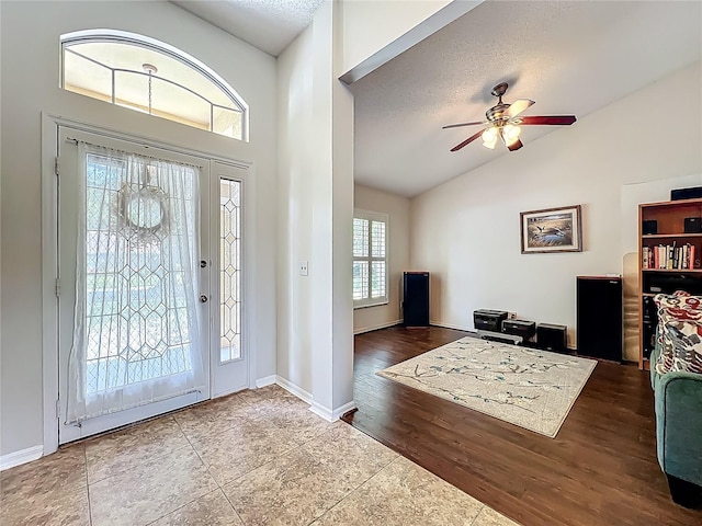 foyer entrance featuring ceiling fan, wood finished floors, a textured ceiling, high vaulted ceiling, and baseboards