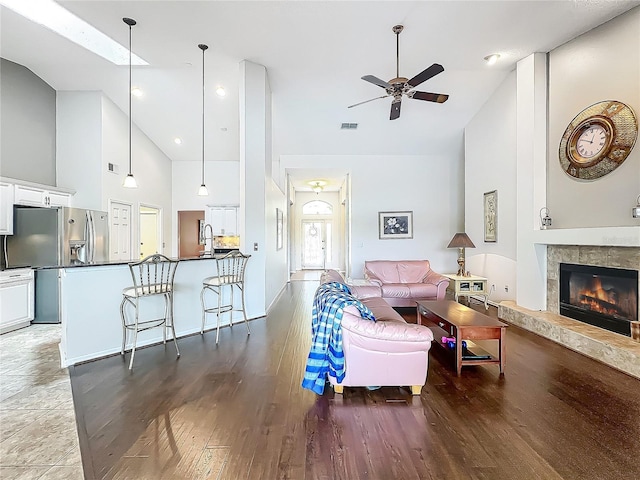 living area featuring high vaulted ceiling, a ceiling fan, a tile fireplace, wood finished floors, and recessed lighting