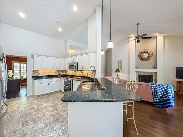 kitchen with appliances with stainless steel finishes, a sink, a peninsula, a kitchen breakfast bar, and a fireplace
