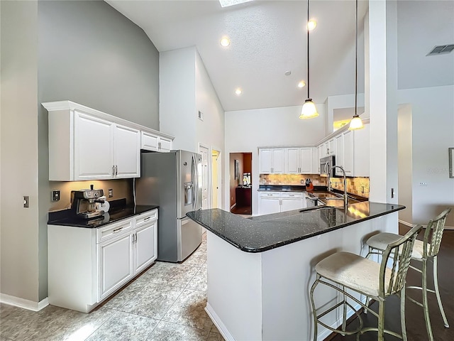 kitchen featuring high vaulted ceiling, appliances with stainless steel finishes, a peninsula, dark countertops, and white cabinets