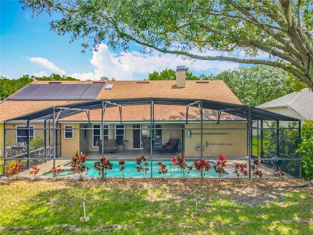 rear view of property featuring glass enclosure, a chimney, roof with shingles, and a patio area