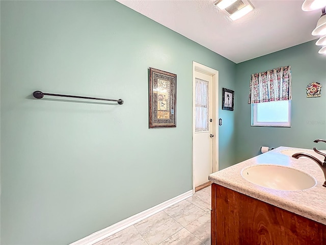bathroom featuring baseboards, marble look tile flooring, and vanity