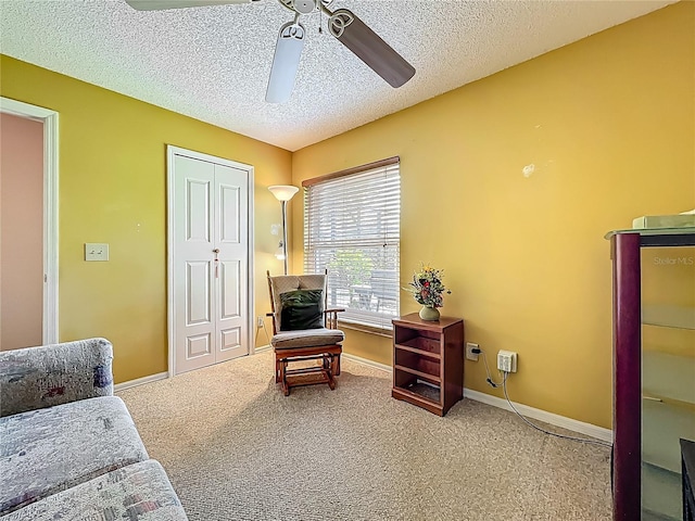living area with ceiling fan, a textured ceiling, carpet flooring, and baseboards