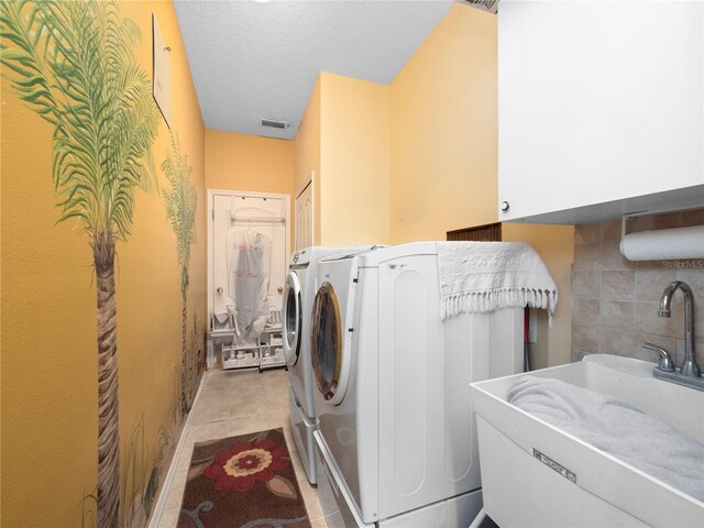 1319 Castleport Rd, Winter Garden, FL 34787 - clothes washing area featuring cabinet space, washing machine and dryer, light tile patterned flooring, and a textured ceiling