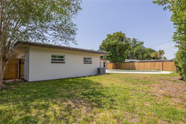 rear view of property with central air condition unit and concrete block siding