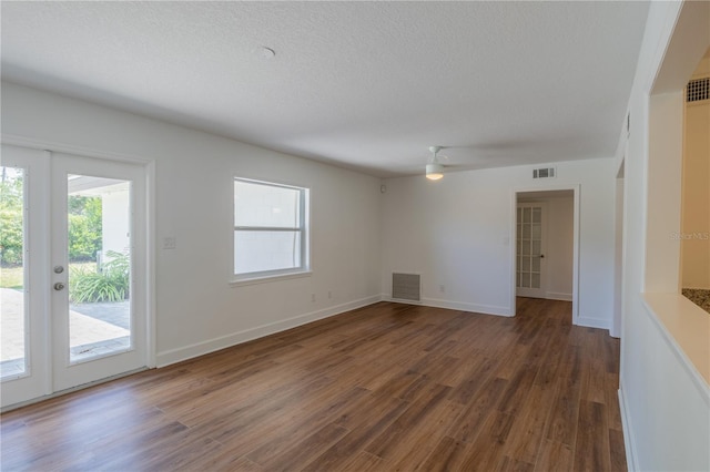 unfurnished living room featuring french doors, healthy amount of natural light, wood finished floors, and a textured ceiling