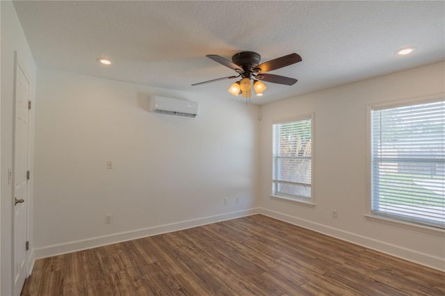 spare room with a wall unit AC, wood finished floors, ceiling fan, baseboards, and recessed lighting