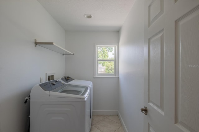 washroom with separate washer and dryer, baseboards, light tile patterned flooring, and a textured ceiling