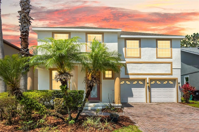 view of front facade with stucco siding, decorative driveway, and an attached garage