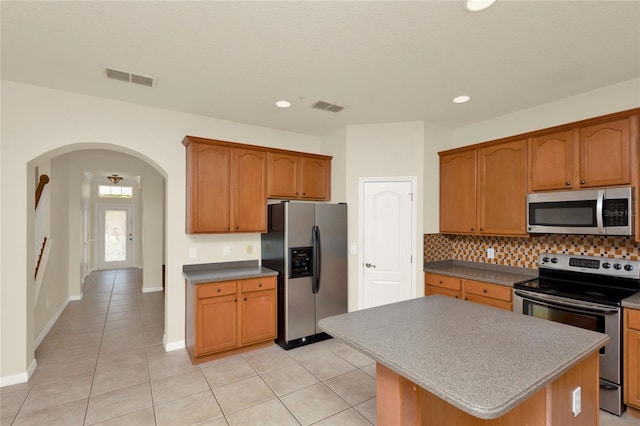 kitchen featuring appliances with stainless steel finishes, arched walkways, backsplash, light tile patterned flooring, and recessed lighting