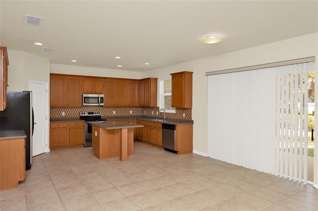kitchen with stainless steel appliances, tasteful backsplash, a kitchen island, light tile patterned floors, and recessed lighting
