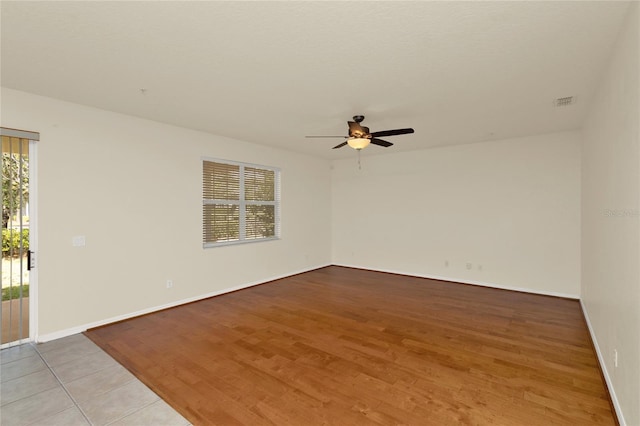 empty room featuring ceiling fan, light wood finished floors, and baseboards