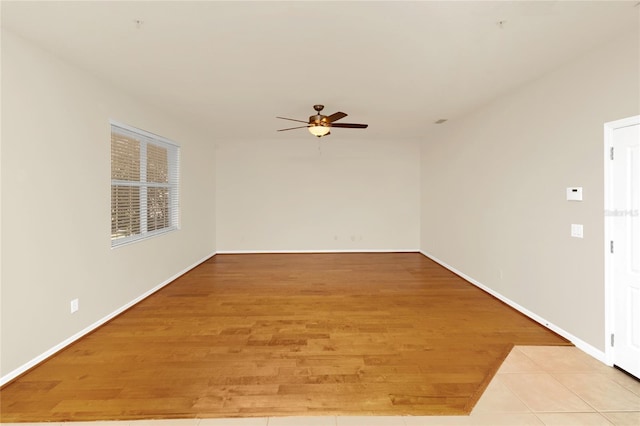 spare room featuring a ceiling fan, light wood finished floors, and baseboards