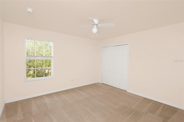 spare room featuring light carpet, baseboards, ceiling fan, and a smoke detector