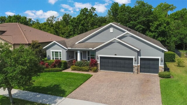 595 American Holly Pl, Oviedo, FL 32765 - view of front of home featuring an attached garage, decorative driveway, a front lawn, stone siding, and stucco siding