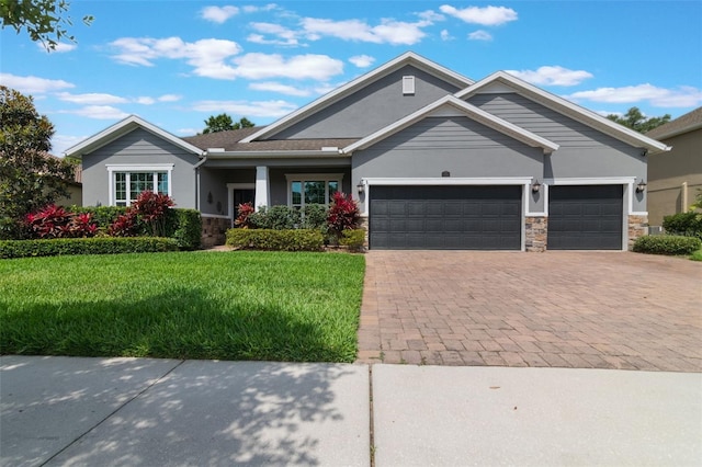 595 American Holly Pl, Oviedo, FL 32765 - craftsman house featuring a front lawn, a garage, decorative driveway, stone siding, and stucco siding