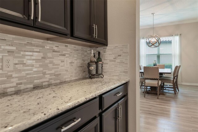 595 American Holly Pl, Oviedo, FL 32765 - kitchen featuring ornamental molding, a chandelier, decorative backsplash, light wood-style flooring, and light stone counters