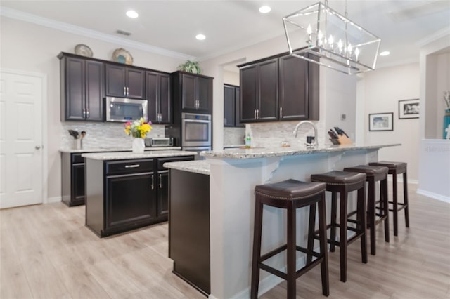 595 American Holly Pl, Oviedo, FL 32765 - kitchen featuring stainless steel appliances, backsplash, a breakfast bar, a chandelier, and crown molding